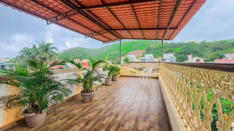 Covered rooftop terrace with plants and hill views